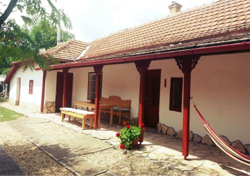 a small white house with a bench and a piano at Árpád nyaralóház in Sarud