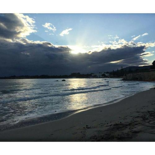 a view of a beach with the sun setting at Villa oasi in Fontane Bianche