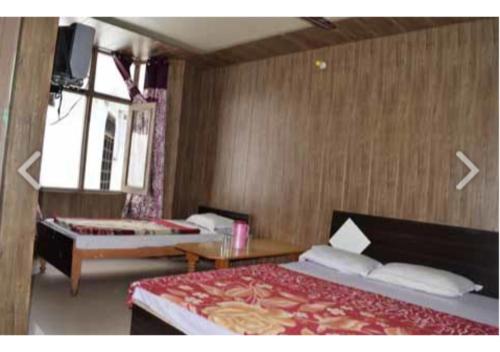 a bedroom with two beds and a table and a window at Ishwari Narayani Hotel in Joshīmath