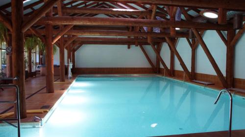 an indoor swimming pool with a wooden ceiling and wooden floors at Domek Żabie Oczko in Jarnołtówek