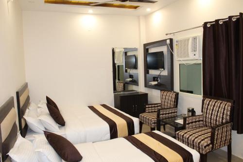 a hotel room with two beds and two chairs at Hotel Gopal in Haridwār