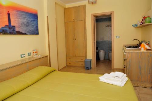 a bedroom with a yellow bed and a bathroom at Cala Dei Normanni - Camere sulle Mura in Otranto
