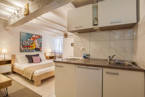 a kitchen and a bedroom with a bed in a room at Honey Art Apartment in Cres