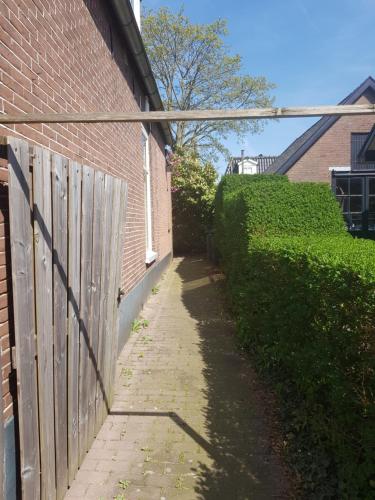 a brick building with a wooden fence next to a sidewalk at Unieke stadswoning voor 2 personen met Finse sauna in Apeldoorn