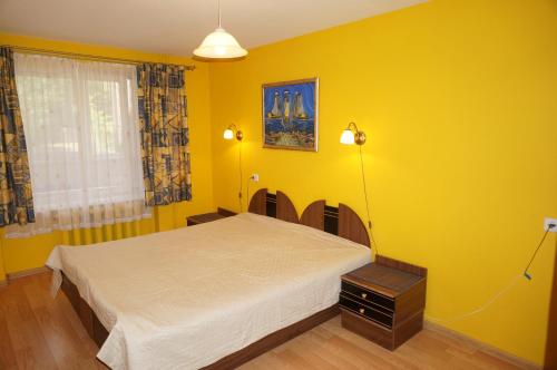a yellow bedroom with a bed and a window at Karolina in Nida