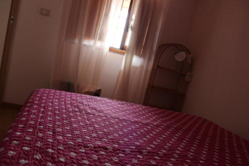 a bedroom with a bed with a red bedspread and a window at Desiderio D'Ammore in Corbara