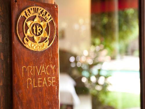 a wooden sign that says prayer please on a pole at Tamukami Hotel in Sanur