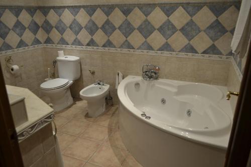a bathroom with a tub and a toilet and a sink at Hotel Arco del Sol in Colmenar