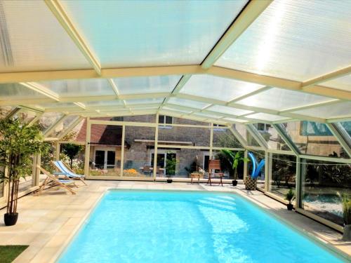 une piscine intérieure avec un plafond en verre dans l'établissement Villa Athéna,séjour bien-être et éthique, à Meuvaines
