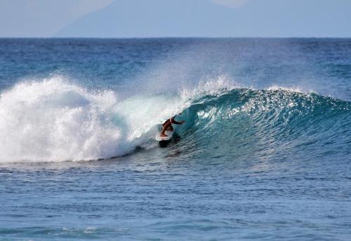 a person riding a wave on a surfboard in the ocean at Ti coin paradis in Anse-Bertrand