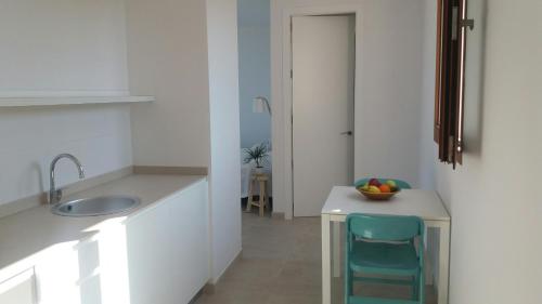 kuchnia ze zlewem i stołem z krzesłem w obiekcie Apartamentos Villa Primera w mieście Cala Figuera