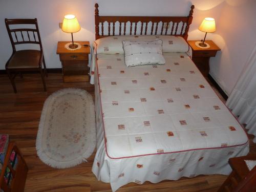 a bedroom with a bed and two chairs and two lamps at Hospedaje Roiz in Suances