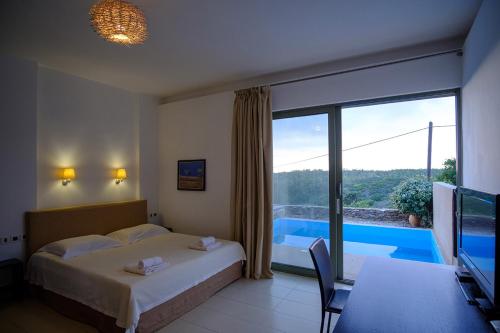 a bedroom with a bed and a tv and a pool at Gerakari Suites in Agia Pelagia Kythira