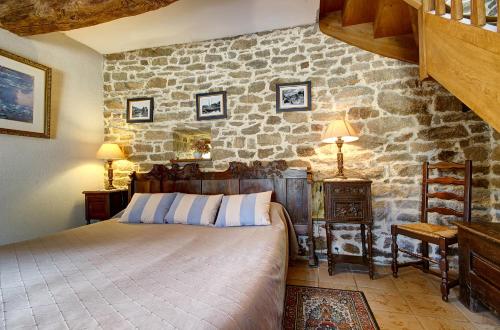 1 dormitorio con cama y pared de piedra en A la Ferme de Kervihern, en Locoal-Mendon