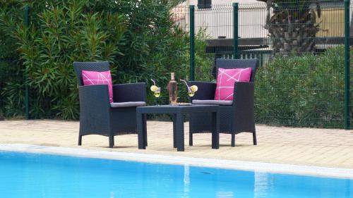 - deux chaises et une table à côté de la piscine dans l'établissement Studio naturiste venus panoramic view, au Cap d'Agde