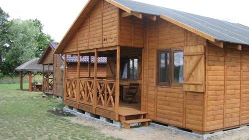 a large wooden cabin with a gambrel roof at Domki Letniskowe ARKON in Strykowo