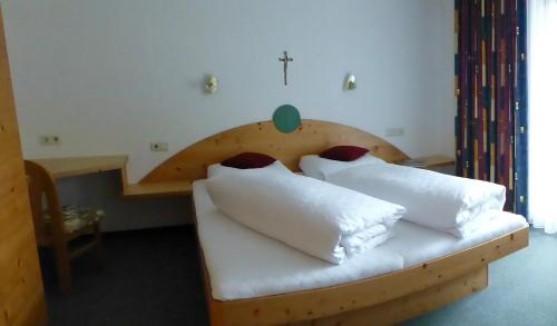 ゼーフェルト・イン・チロルにあるGästehaus Manuela - Familie Rantnerのベッドルーム1室(白い枕の木製ベッド1台付)