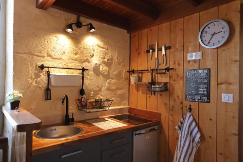 Una cocina con un fregadero y un reloj en la pared. en Les Appartements de la Victoire, Centre-ville, Parking GRATUIT, en Burdeos