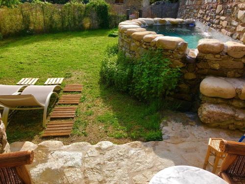 a backyard with a swimming pool and a stone wall at U Fragnu in Omessa