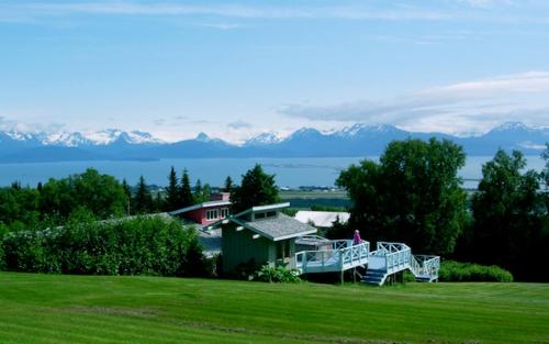 a house in a field with mountains in the background at Halcyon Heights B&B/Inn in Homer
