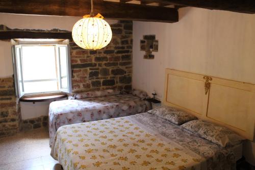 a bedroom with two beds and a window and a chandelier at B&B Paradiso in Gubbio