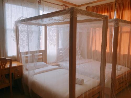 two beds in a bedroom with a canopy bed at Hotel Duomo and Suites in Kampala