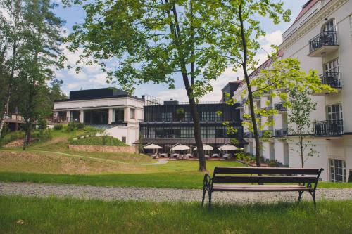 a park bench in the grass in front of a building at Hotel SPA Dr Irena Eris Polanica Zdrój in Polanica-Zdrój