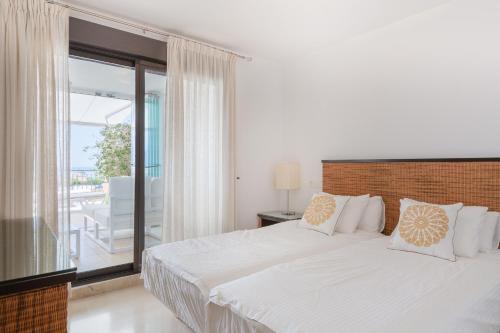 a white bedroom with a bed and a balcony at Apartamento Calaceite in Torrox Costa