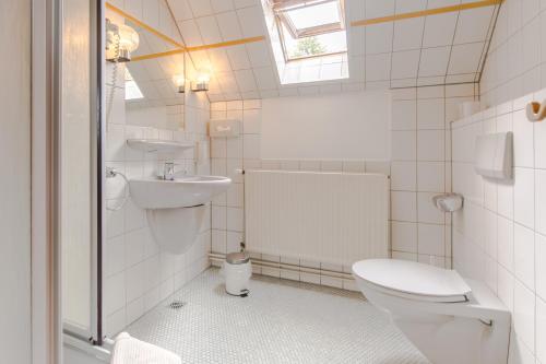 a white bathroom with a toilet and a sink at Hotel Johnsburg in Uelzen