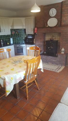 a kitchen with a table and chairs with a clock at Tulla Villa Self Catering in Riverstown