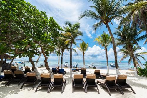 a man sitting at a table on a beach with palm trees at Playa Palms Beach Hotel in Playa del Carmen