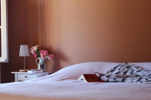 a bedroom with a white bed with a book on it at Maison Poche in Caupenne-dʼArmagnac