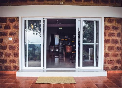 an open sliding glass door on a brick wall at Forestdale Coorg in Virajpet