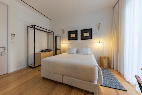 a bedroom with a large white bed and a mirror at Sapientia Boutique Hotel in Coimbra