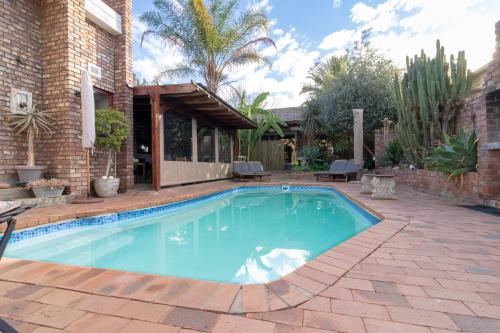 una piscina en un patio con una casa en Earthbound Guest House, en Oudtshoorn