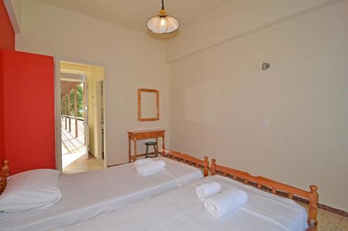 2 Betten in einem Zimmer mit roter Wand in der Unterkunft Levante taverna studios in Alikanas