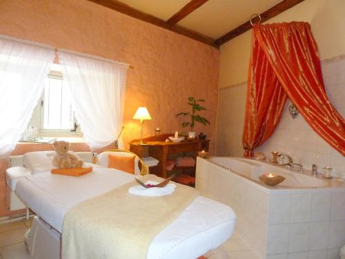 a bedroom with a bed and a tub and a teddy bear at Hotel & Spa Wasserschloss Westerburg in Westerburg