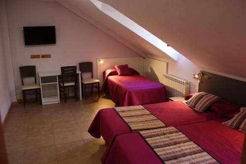 a room with two beds and a table and chairs at Hostal La Ribera del Júcar in Cuenca