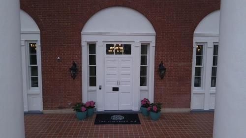 a white door in a brick building with potted plants at The Blackburn Inn and Conference Center in Staunton