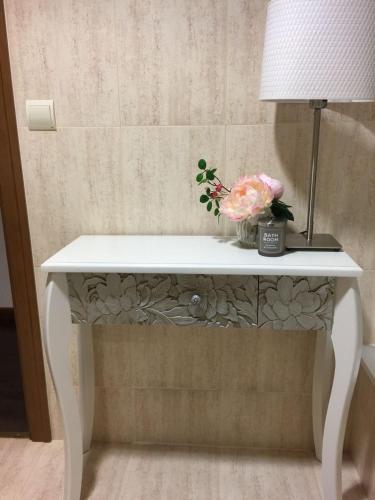 a white table with a lamp and flowers on it at Badaguas It's Cozy in Badaguás