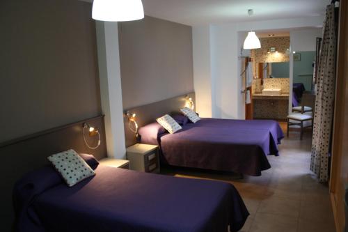 a hotel room with two beds and a bathroom at Hostal La Ribera del Júcar in Cuenca