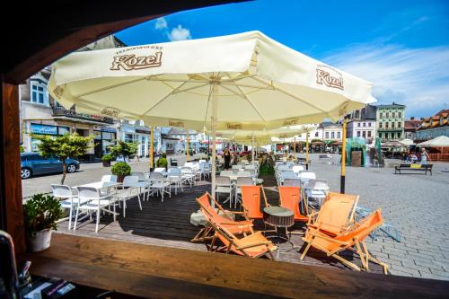 een groep stoelen en een paraplu op straat bij Inna Strefa - Sleep & Restaurant in Inowrocław