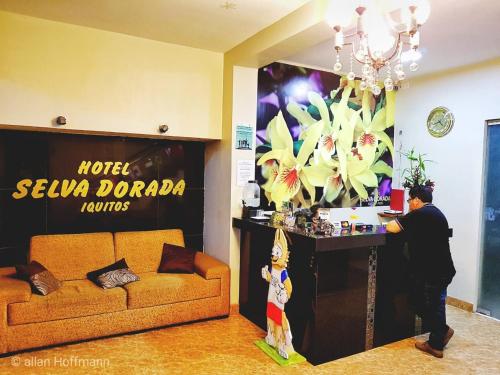 a man standing at a counter in a room with a couch at Hotel Selva Dorada in Iquitos