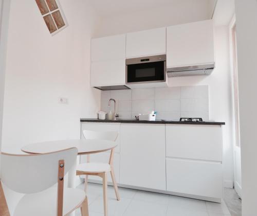 een witte keuken met een tafel en een magnetron bij Iris Amalfi Dreams in Minori