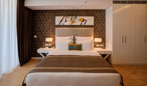 a bedroom with a large bed with two tables and two lamps at Lancaster Eden Bay in Beirut
