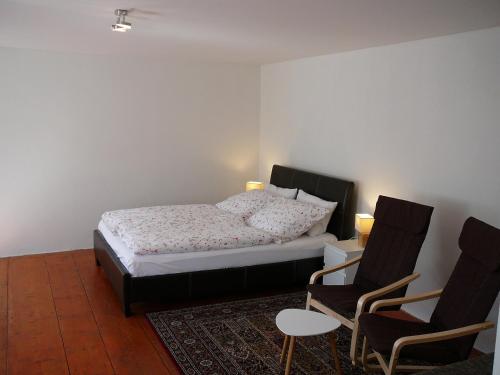 a bedroom with a bed and two chairs at Apartman Modry dum in Vranov nad Dyjí