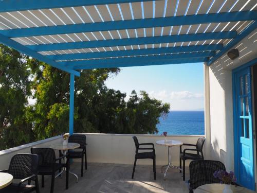 eine Terrasse mit Tischen und Stühlen und Meerblick in der Unterkunft Arkas Inn in Logaras