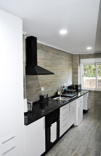 a kitchen with white cabinets and a black counter top at Belém River Apartment II in Lisbon