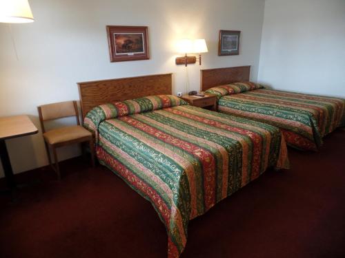 una habitación de hotel con dos camas y una mesa en Dakota Country Inn, en Platte