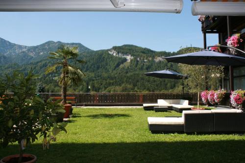 a patio with couches and umbrellas with a mountain at Hotel Lindwurm in Bad Goisern